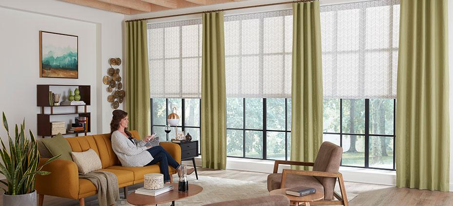Woman in living room with controlling her motorized window treatments
