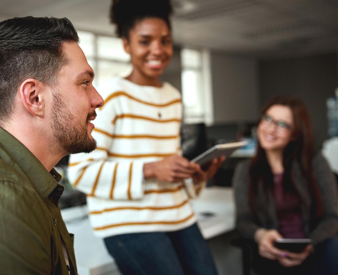 Smiling team members listen intently as a colleague offers their thoughts during a meeting.